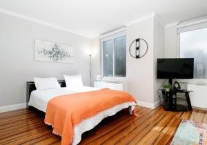ein weißes Schlafzimmer mit einem Bett und einem Flachbild-TV in der Unterkunft Lovely Studio Apartment in NYC in New York