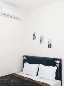 Una cama con un cabecero negro con tres cuadros en la pared en Bunda House Syariah Lapai, en Padang