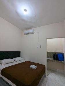 Habitación blanca con cama y espejo en Bunda House Syariah Lapai, en Padang