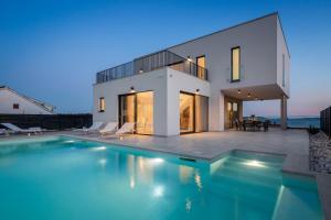 ein Haus mit einem Pool vor einem Haus in der Unterkunft NEW! Villa Brilliance heated pool 50 m2, sea view in Vranjic
