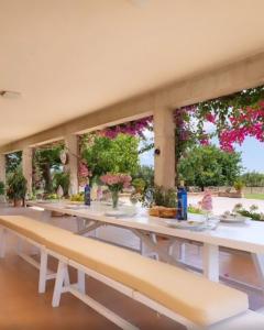 ein Esszimmer mit Tischen, Bänken und Blumen in der Unterkunft Villa Darder , Sa garriga in Ariany