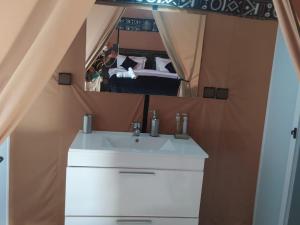 a bathroom with a sink and a mirror and a bed at Global Luxury Camp in Merzouga