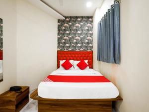 a small bedroom with a bed with red pillows at Hotel King Residency in Mumbai