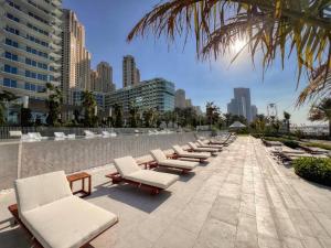 a row of chaise lounges and chairs on a beach at Fantastic and Rare 4BR+maid's in JBR Walk in Dubai