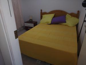 małą sypialnię z łóżkiem z żółtymi poduszkami w obiekcie RESIDENCE BAHIA REAL PUERTO de MAZARRON w mieście Puerto de Mazarrón