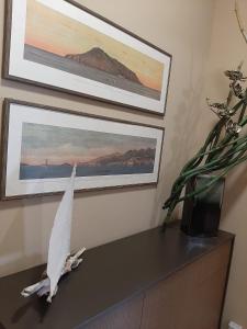 una estatua de pájaro en una mesa con dos cuadros en la pared en LARANDA rooms en Milazzo