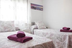 two beds with purple towels on them in a room at La Mar Sala by key-wise in Rincón de la Victoria +23 photos