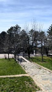 a stone path in a park with trees and a fence at CHALET VERDE in Kirazlı