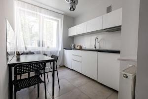 een keuken met witte kasten en een tafel en stoelen bij Golden Apartments&Widok in Wrocław