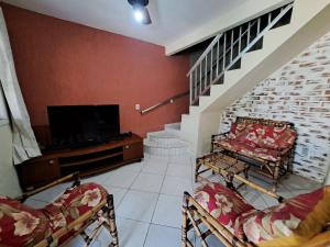 a living room with a flat screen tv and chairs at Linda Casa 4 qts churrasqueira Prainha Mambucaba in Paraty