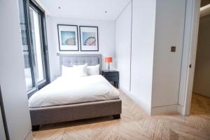 a white bedroom with a bed and a window at Cosmopolitan Hideaway in London