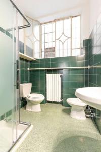 a green tiled bathroom with two toilets and a sink at Appartamento al Duomo di Parma - posto auto privato prenotabile in Parma