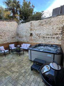 a hot tub on a patio with a brick wall at Maison en pierre avec jacuzzi in Caen