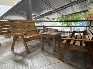 grupa drewnianych ławek siedzących wewnątrz budynku w obiekcie Auberge-Cafe Tunisie w mieście Nawakszut