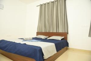 Sai Homestay Panaji Studio في باناجي: غرفة نوم بسرير وملاءات زرقاء ونافذة