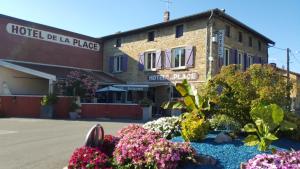 a building with a bunch of flowers in the street at Hotel de la Place in Loyettes