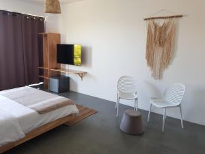 1 dormitorio con 2 sillas, 1 cama y TV en Villas Rocher - Standard Suite 2B en Grand Baie
