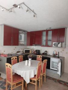 une cuisine avec des placards rouges et une table avec des chaises dans l'établissement Kuća za odmor, à Žitomislići