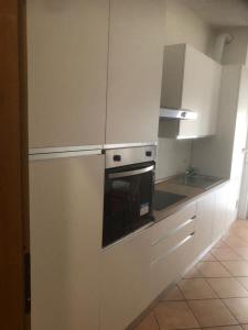 een keuken met witte kasten en een oven bij Tiffany Suites Cesano in Cesano Boscone