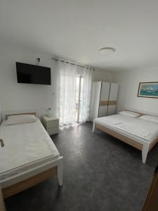 Un dormitorio con dos camas y un televisor de pantalla plana. en Apartmani Požega, en Pag