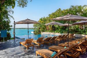 a swimming pool with wooden chairs and umbrellas at Cristalino Lagoon Front Hotel, Restaurant & Spa in Bacalar
