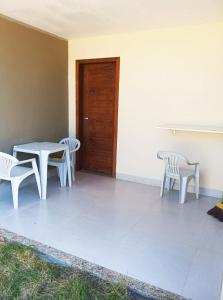 eine Terrasse mit einem Tisch, Stühlen und einer Tür in der Unterkunft Casa Luxo e Sossego 50m da Praia in Guriri