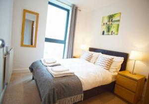 a bedroom with a bed with white sheets and a window at Excel - O2 Arena - 2 Bed Apartment Parking & Netflix in London