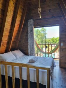 a bed in a log cabin with a large window at Chalés Ilha da Mata Pousada in Florianópolis