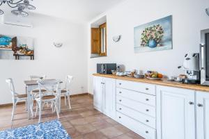 cocina con armarios blancos y mesa en Villa Prota, en Vico Equense