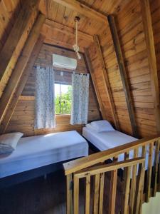 two beds in a log cabin with a window at Chalés Ilha da Mata Pousada in Florianópolis