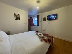 a bedroom with a white bed with a tv on the wall at Crompton Haven, Liverpool Accessible Home in Liverpool