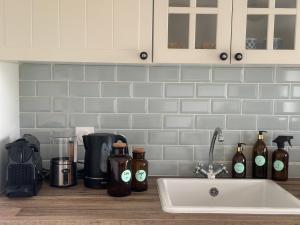 a kitchen counter with bottles of alcohol and a sink at La Maison de Melman in Quettreville-sur-Sienne +81 photos