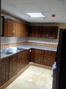 a kitchen with wooden cabinets and a sink at 1 BHK Fully Furnished Flat in Sharjah