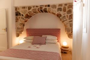 1 dormitorio con 1 cama con pared de piedra en Tenuta Lavati, Santa Maria di Leuca, en Castrignano del Capo