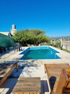 a swimming pool with a table and two benches at Terrazas de Estancia in Villa Carlos Paz