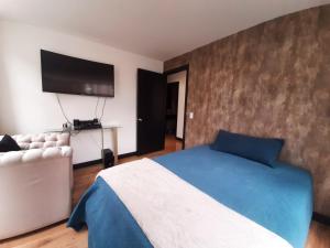 um quarto com uma cama e uma televisão na parede em CONFORTABLE Y ELEGANTE DEPARTAMENTO em Quito