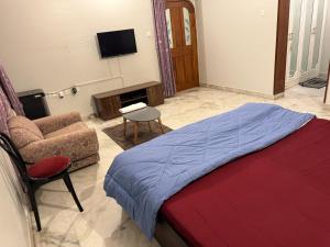 ein Schlafzimmer mit einem Bett, einem Sofa und einem TV in der Unterkunft Riya Villa (Kaashi Flora Unit) in Varanasi