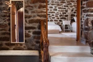 Zimmer mit einer Steinmauer, einem Bett und einem Spiegel in der Unterkunft peaceful place in Anítsaion