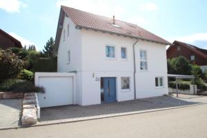 a white house with a blue door and a garage at TOP Ferienwohnung in Bad Urach