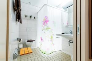 La salle de bains est pourvue d'un rideau de douche et de fleurs. dans l'établissement Hotel Restaurant Sokrates, à Güttingen