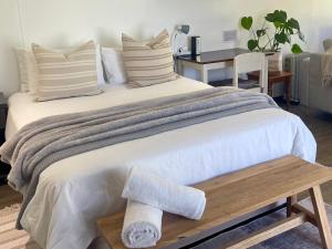 a large white bed with a wooden bench next to it at Nahoon Studio in East London