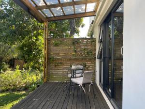 a wooden deck with a table and a pergola at Nahoon Studio in East London