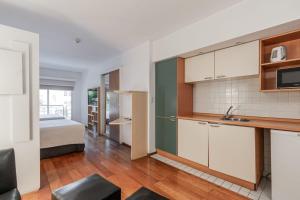 a kitchen with white cabinets and a bed in a room at Apart Hotel Rio Grande in Rosario