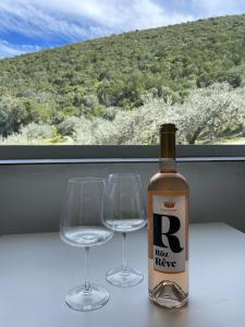 una botella de vino y dos copas de vino en una ventana en Orange Apartments, en Epáno Epídhavros