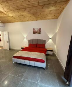 um quarto com uma cama vermelha num quarto com tectos em madeira em Qyteza Guest House & Camping em Shkodër