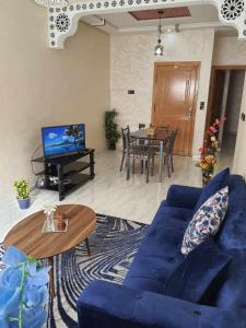 Appartement Dar Meknès في مكناس: غرفة معيشة مع أريكة زرقاء وطاولة