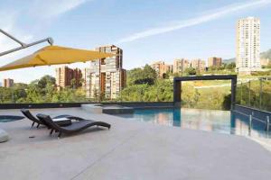 eine Terrasse mit einem Pool, einem Sonnenschirm und Stühlen in der Unterkunft 1102, Best View Beautiful Apartment El Poblado in Medellín