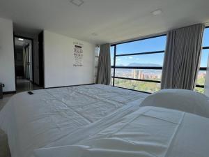 ein großes weißes Bett in einem Zimmer mit einem großen Fenster in der Unterkunft 1102, Best View Beautiful Apartment El Poblado in Medellín