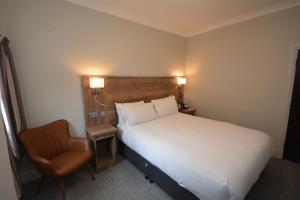 una habitación de hotel con una cama y una silla en The Rugby Hotel, en Rugby