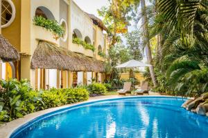 a swimming pool in front of a hotel with palm trees at Hotel Villas Sayulita in Sayulita